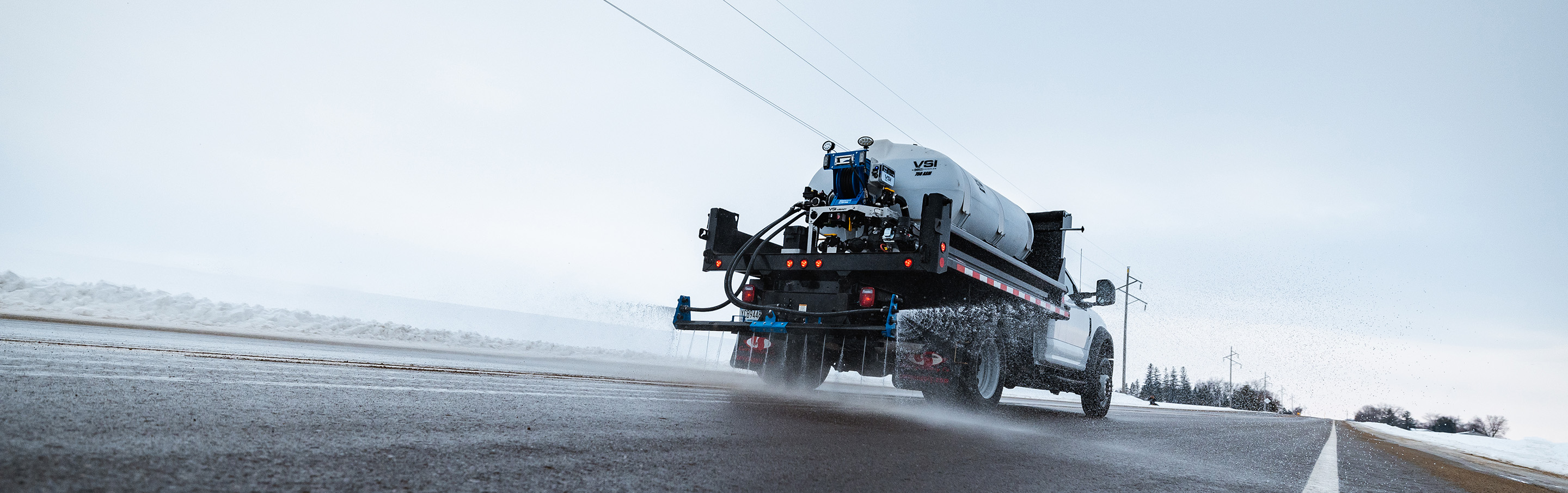 Photo of of the back of a truck with a VSI de-icer spraying the road