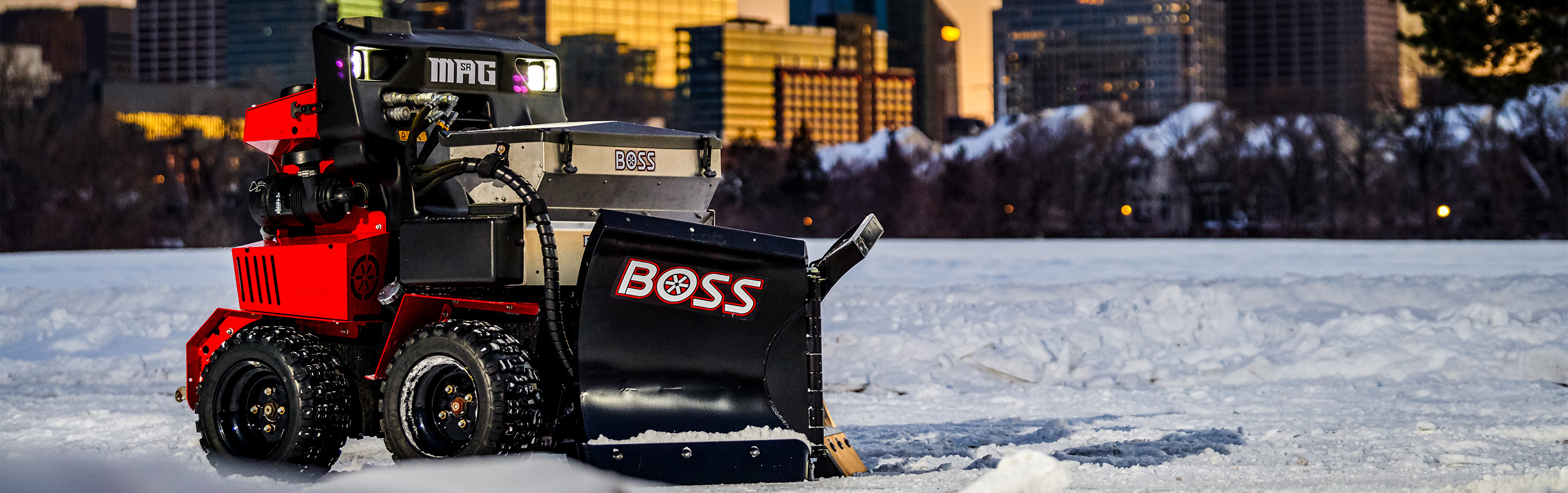 Photo of an SR MAG with a v-plow attachment and a city skyline in the background